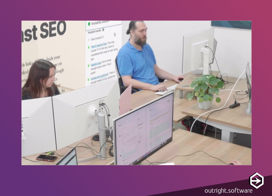 a purple - magenta border and a photograph of two people working on large computer screens in an office - probably Yoast employees.